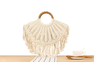 Detail of bohemian woven cotton bag with round wooden handles and long decorative fringes
