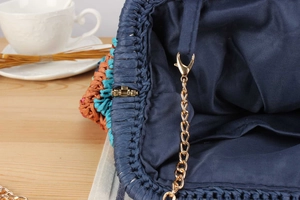 Detail of multi-color woven straw bag with blue fabric lining and gold snap closure