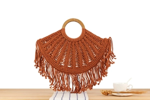 Detail of bohemian hand-woven cotton bag with round wooden handle and long fringe tassels