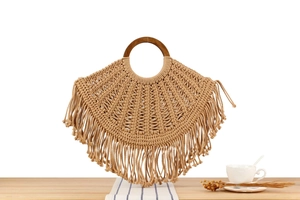 Detail of bohemian woven handbag with wooden ring handle and long fringe tassels