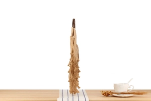 Detail view of woven cotton rope bag with tiered tassels and round dark handles