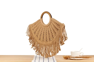 Detail of bohemian handmade cotton rope bag with round wood handles and long tassels