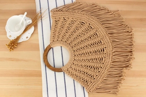 Detail of bohemian woven cotton bag with fringe trim and round wooden handle