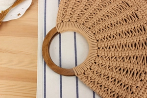 Detail of hand-woven cotton bag with a round wooden handle on a rustic wooden table