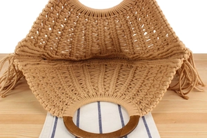 Close-up of handmade macrame bag with circular wooden handles and stylish side tassels