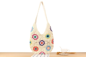 Close-up of handmade crochet tote bag with colorful sunflower patterns on beige cotton yarn