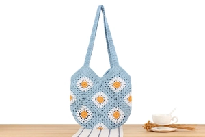 Detail einer hellblauen Baumwolltasche mit handgehäkelten weißen Gänseblümchen-Blumenmustern