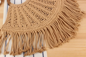 Detail of handmade woven cotton bag with wooden ring handle and long boho tassels