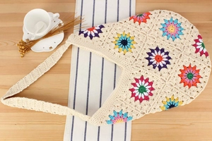 Detail of colorful granny square crochet flowers on an off-white cotton woven tote bag