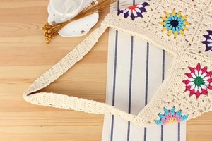 Close-up of hand-crocheted tote bag featuring colorful sunflower patterns and textures