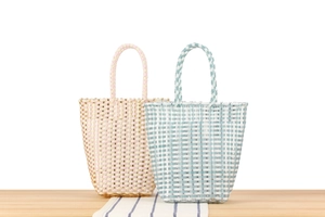Detail of pink and blue woven plastic tote bags with sturdy handles on a wooden table
