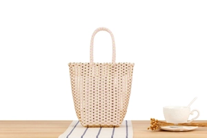 Detail of hand-woven plastic tote bag with beige and pink patterns for seaside vacations