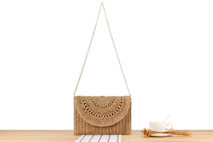 Close-up of light brown crochet chain bag with hollow round weave on wooden table