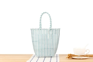 Detail of light blue and white checkered hand-woven plastic bag on a wooden table