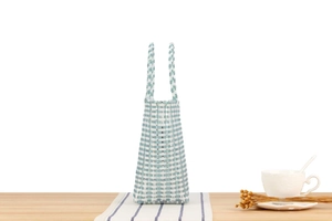 Close-up of light blue and white checkerboard woven tote bag on a wooden table