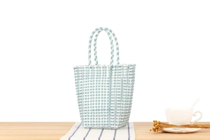 Detail view of light blue and white woven tote bag on a rustic table setting