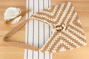 Sac à bandoulière au crochet fait main avec motif géométrique bicolore et détail en anneau bois.