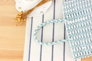 Close-up of light blue and white plastic woven texture on a casual vacation tote bag
