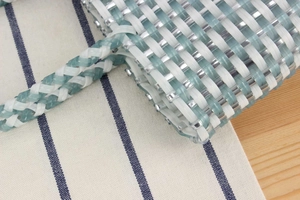 Detail shot of the blue and white woven plastic handbag with intricate checkerboard pattern
