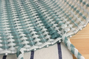 Macro detail of hand-woven plastic tote bag featuring teal and cream textures
