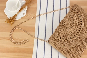 Detail of hand-woven crochet bag texture with gold chain strap on a rustic table