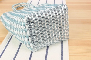 Close-up of blue and white hand-woven plastic tote bag with detailed grid texture