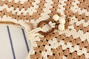 Gros plan sur les détails d'un sac tissé en coton bicolore fait main avec anneau et perles en bois.
