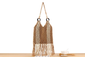 Detail of bohemian woven bag with tassels, wooden rings and beads on a rustic desk