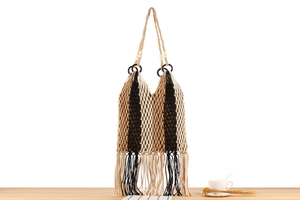 Detail of bohemian hand-woven mesh bag with tassels and wooden bead on handle