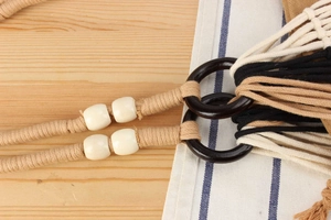 Detail of bohemian handmade woven bag with cotton rope tassels and wooden ring accents