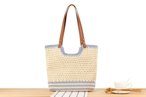 Detail of blue striped woven tote bag with brown leather handles on wooden surface
