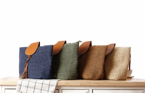 Detail of woven straw shoulder bags with leather tassels and wooden buttons in four colors