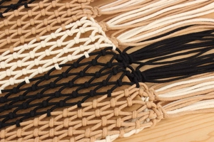 Detail of handmade hollow woven bag with multi-color knots and long tassel fringe
