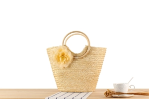 Détail d'un sac cabas en paille avec fleurs décoratives et anses rondes en bois