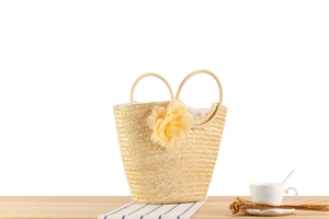 Détail du sac cabas en paille avec anse en rotin et grande fleur en mousseline décorative