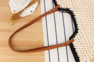 Detail of woven tote bag featuring beige crochet, black lace trim, and leather handles