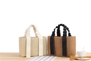 Detail of woven paper rope tote bags in two colors with decorative ribbon handles