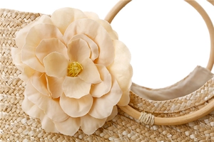 Détail d'un sac en paille tissée avec fleur en velours rose et anse ronde