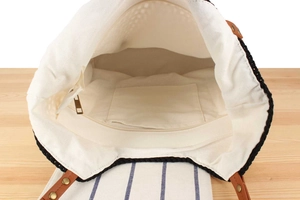 Internal view of the woven tote bag featuring a zipper pocket and canvas lining texture