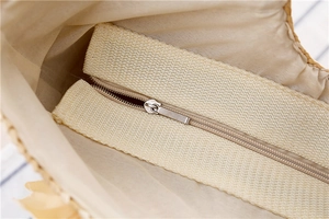 Détail du sac en paille tressée avec fermeture éclair métallique et doublure crème
