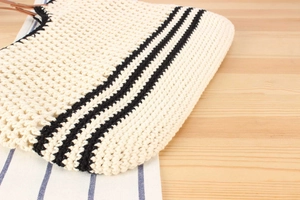 Detailed view of woven tote bag with beige fiber texture and black striped accents
