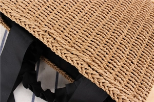 Detail of woven straw handbag showing the black fabric lining and ribbed handles