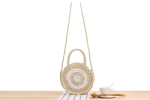 Détail du sac en paille tissée avec rayures circulaires, poignées et bandoulière