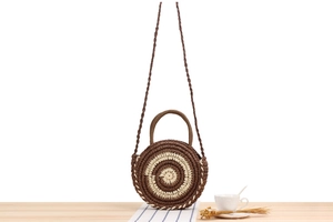 Détail du sac rond en paille avec texture en spirale rayée et bandoulière longue