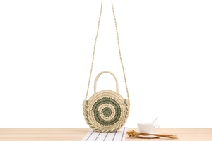 Détail d'un sac rond en paille avec tissage en spirale verte sur une table pour l'été
