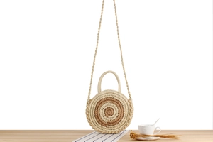 Détail du sac de plage rond en paille avec motif rayé beige et double poignée porté