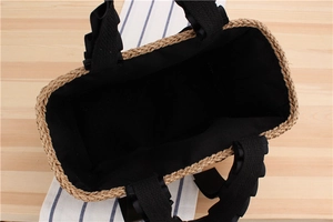 Detail view of woven straw tote bag with black wavy ribbon handle and spacious inner lining