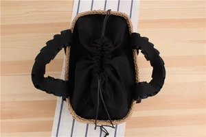 Detailed top view of a rectangular straw tote with black drawstring liner and pleated handles