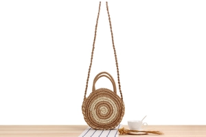Détail du sac rond en paille tressée à rayures avec poignée et bandoulière de vacances