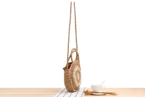 Gros plan d'un sac rond en corde de papier tissé à la main avec rayures beiges et poignées